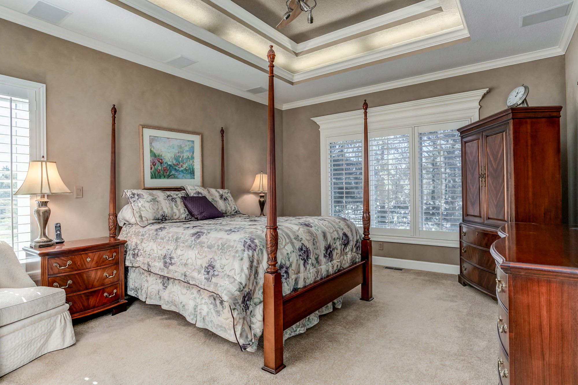 The captivating main level master suite showcases custom paint, and a multi-tiered recessed ceiling with lighted ceiling fan and indirect lighting.