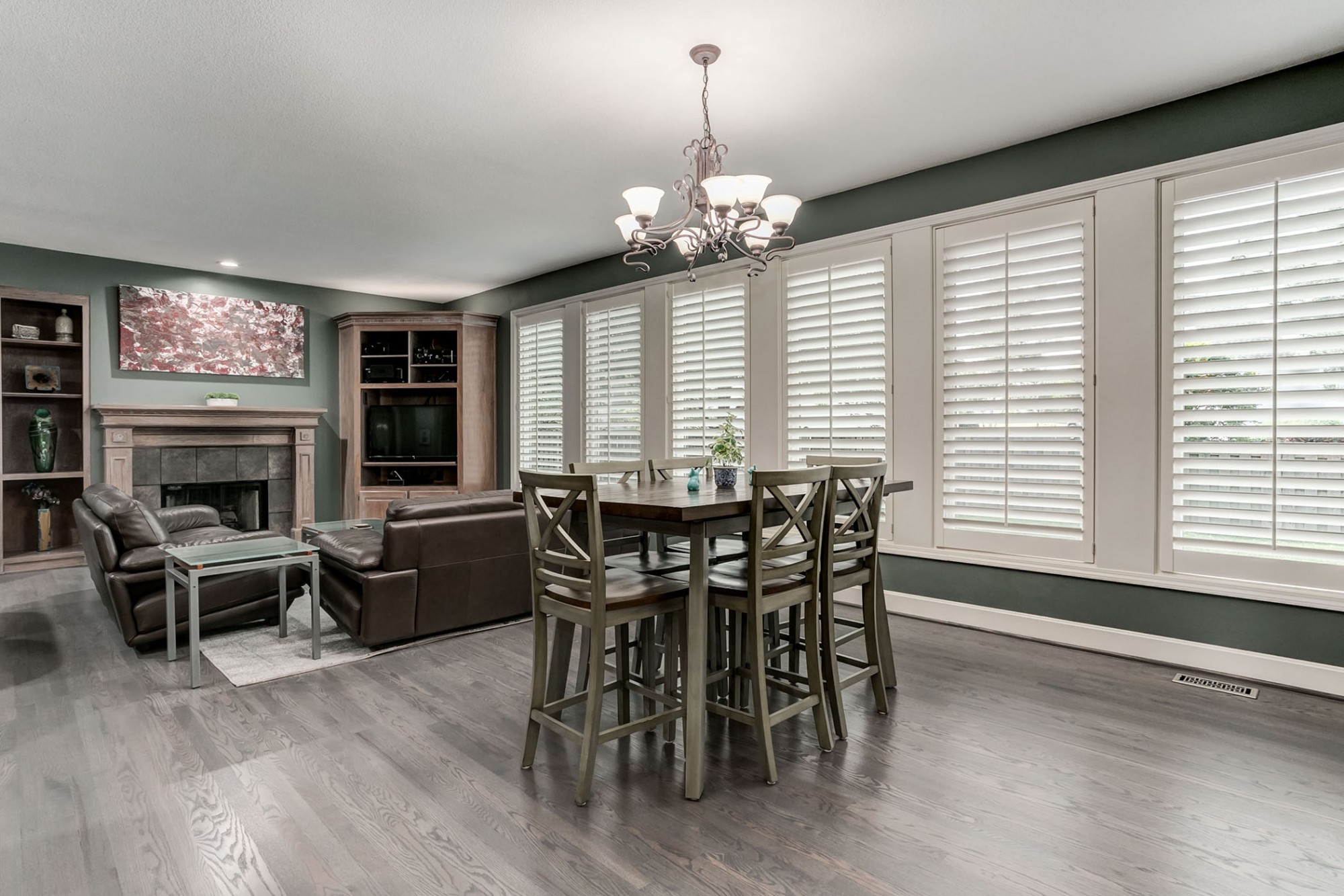 Newly refinished hardwoods beautifully displayed in the family dining area accented by a wall of plantation shutters.