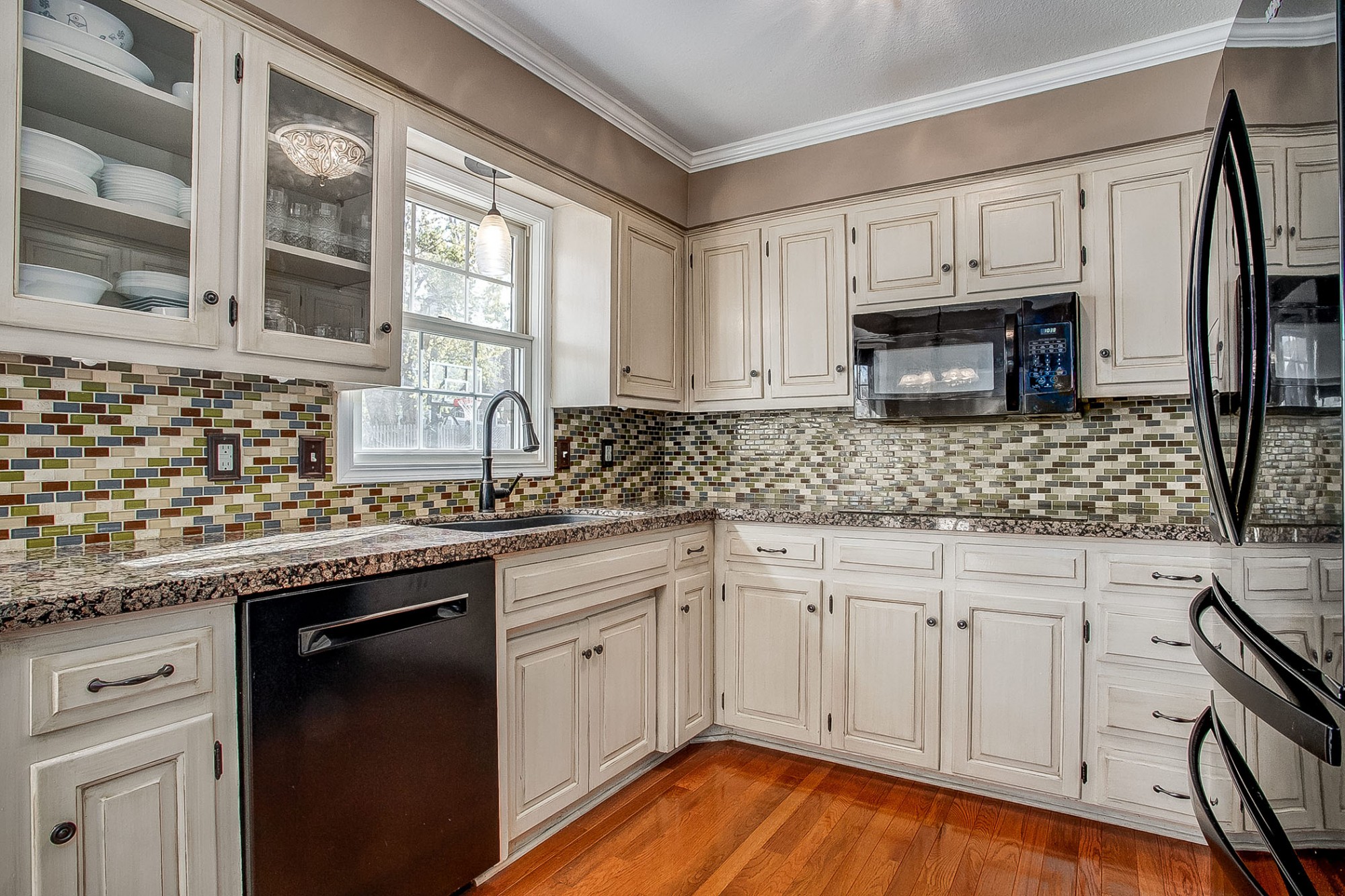 Abundant cottage white cabinetry, gorgeous granite counters, wood floors, and full glass tile mosaic backsplash.